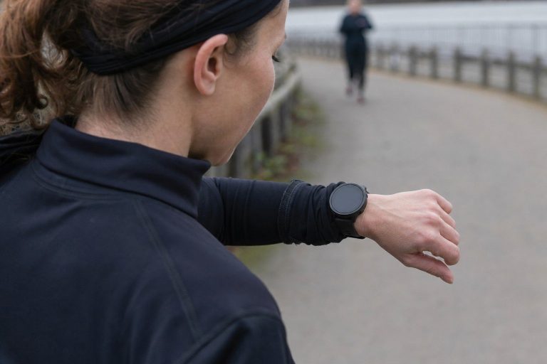 Close-up of a runner glancing at a plain GPS watch mid-run