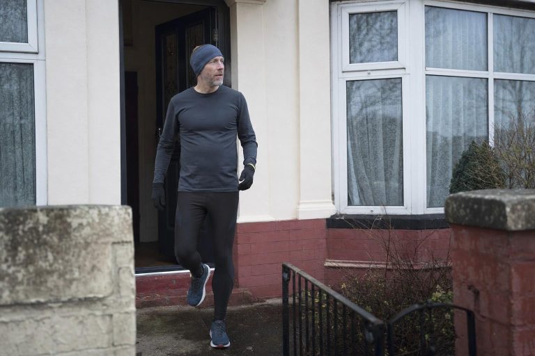 A runner heading out the door into a cold grey winter morning
