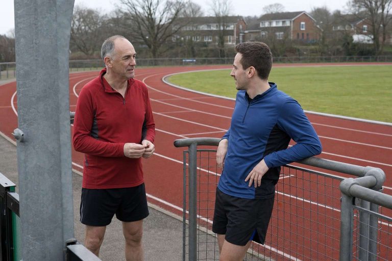 Two runners talking at the side of a running track